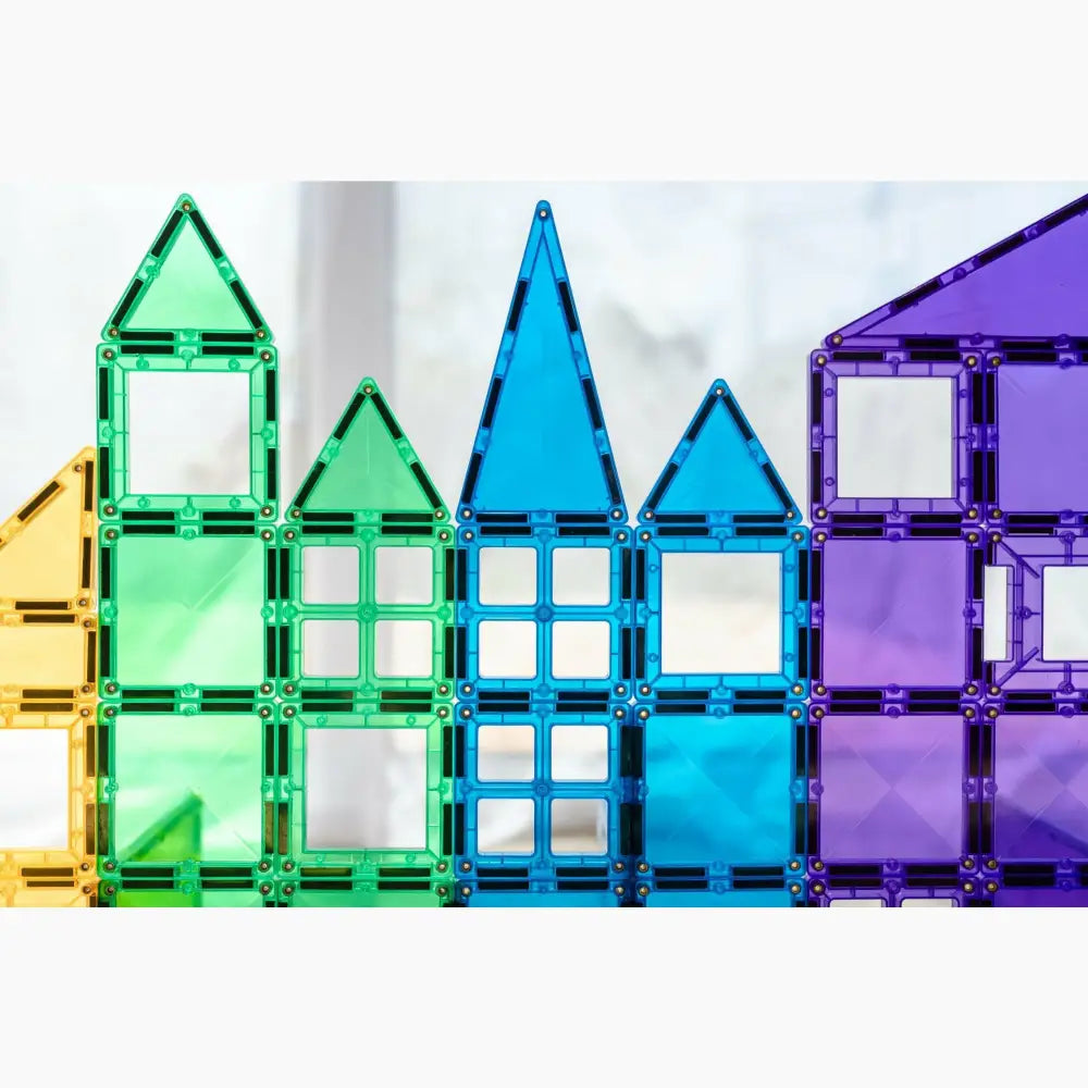 Colorful magnetic building tiles arranged to form house-like shapes.