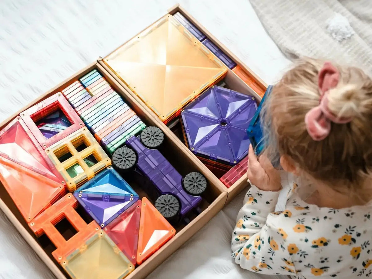 Wooden box filled with colorful geometric building blocks and shapes.