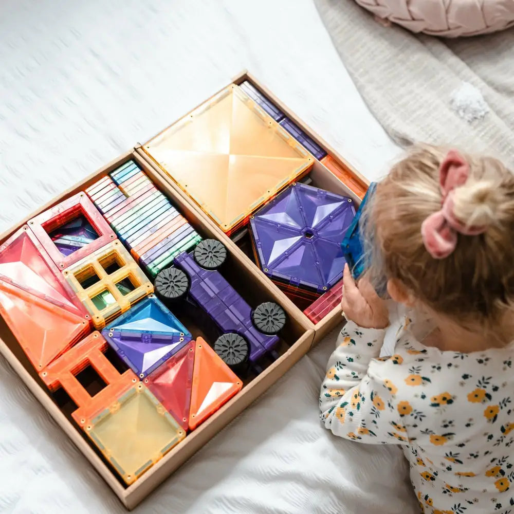 Wooden box filled with colorful geometric building blocks and shapes.