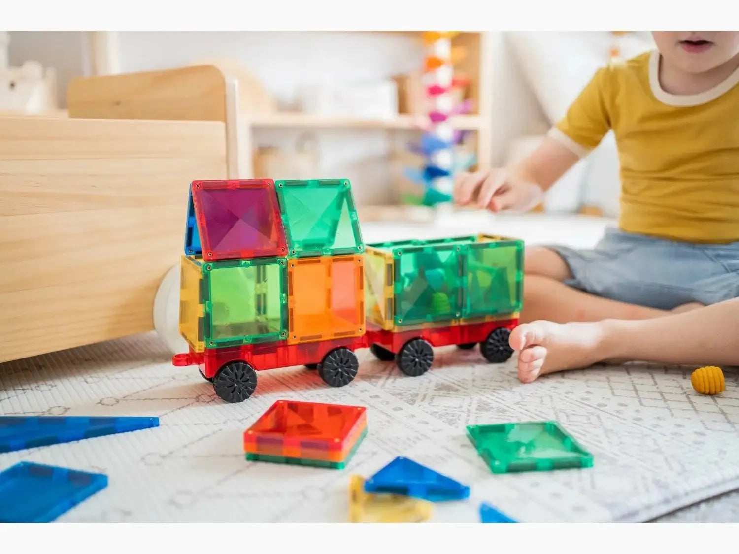 Colorful magnetic building tiles assembled into a toy train shape.