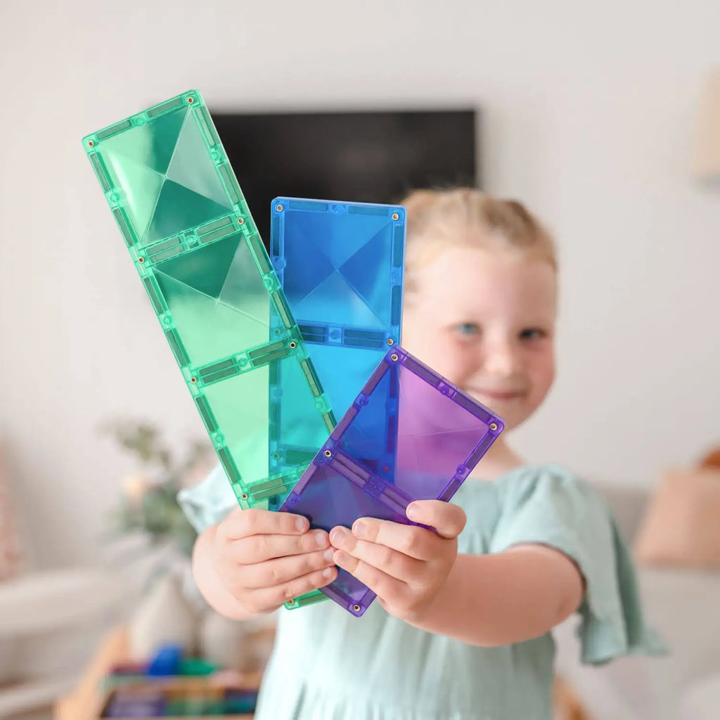 Colorful magnetic building tiles held by small hands.