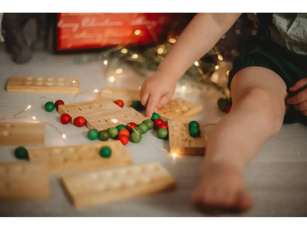 Wooden Jenga blocks scattered with red and green Christmas ornaments.