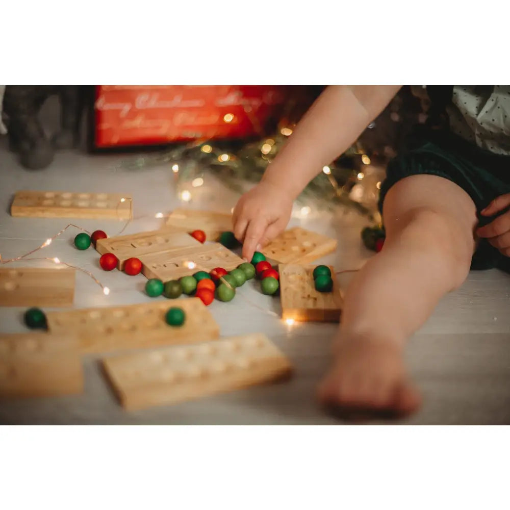 Wooden Jenga blocks scattered with red and green Christmas ornaments.