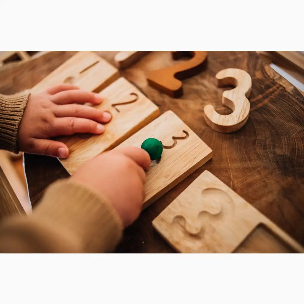 Wooden number puzzle pieces with small hands interacting with them.