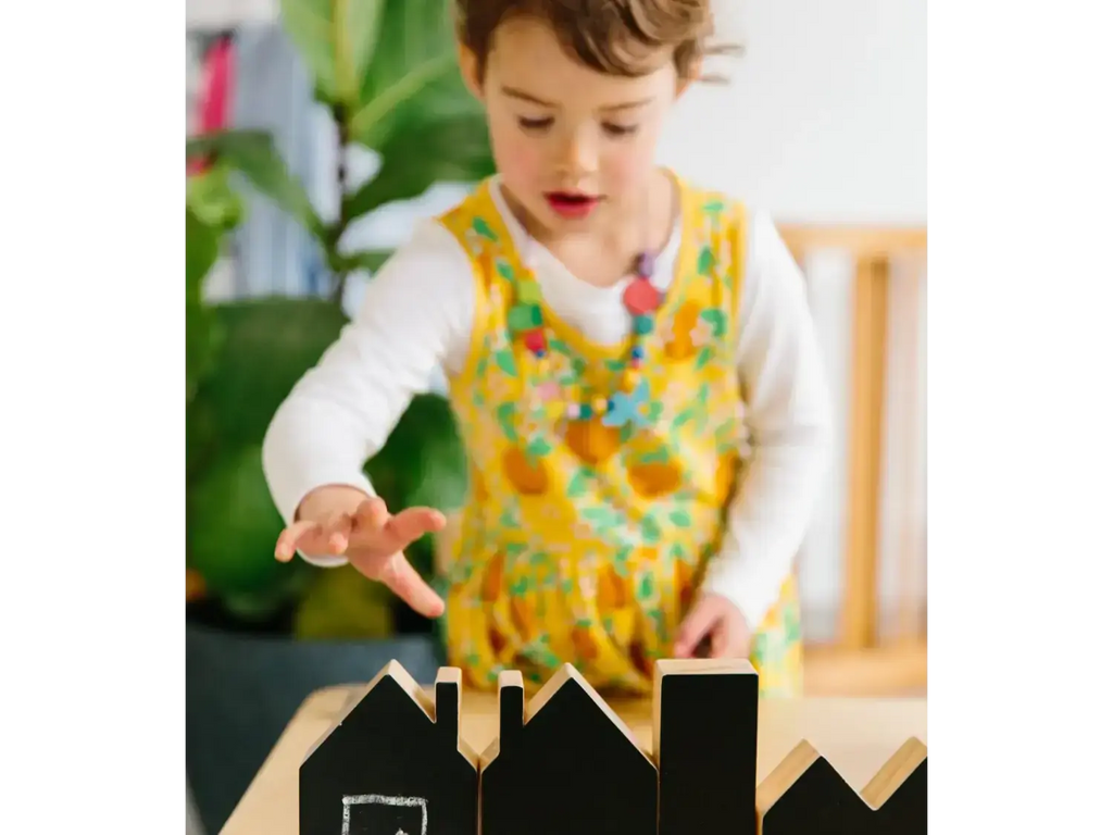 Child playing with wooden block houses on a table.