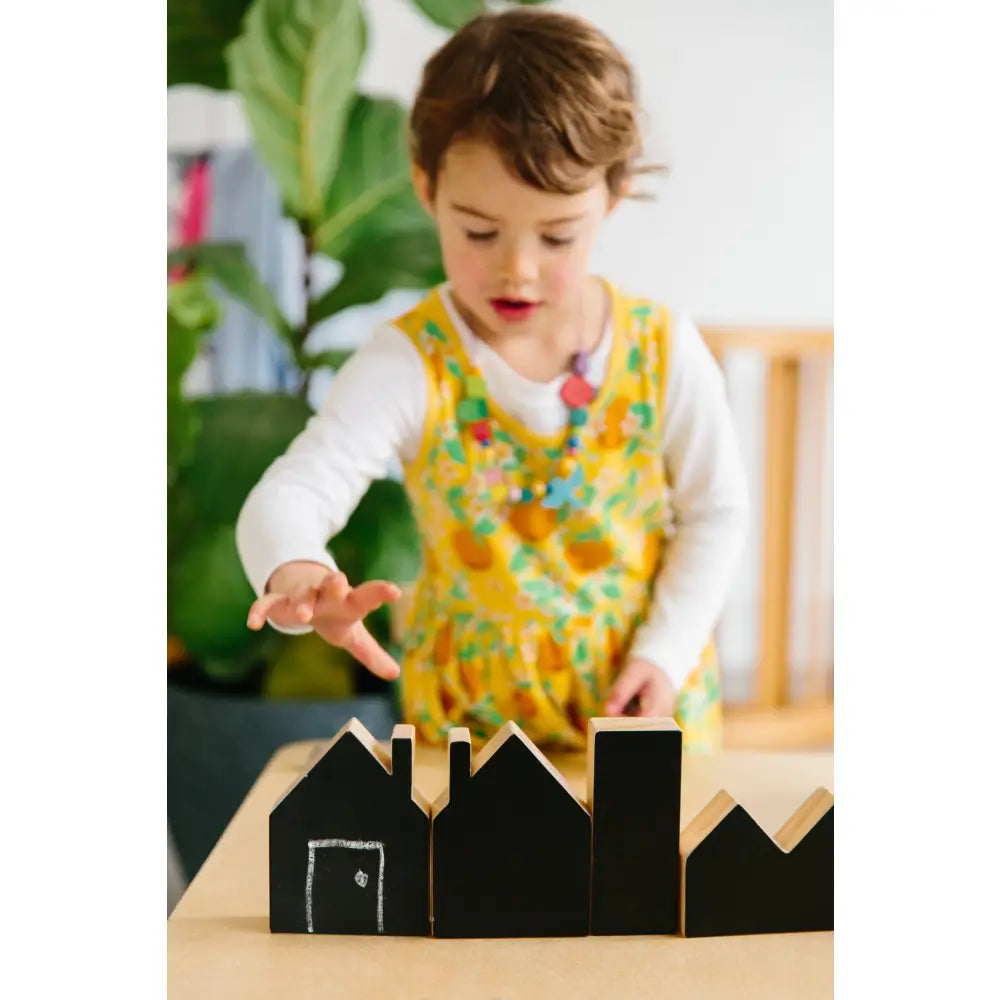 Child playing with wooden block houses on a table.