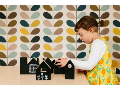 Child playing with small wooden house-shaped blocks.