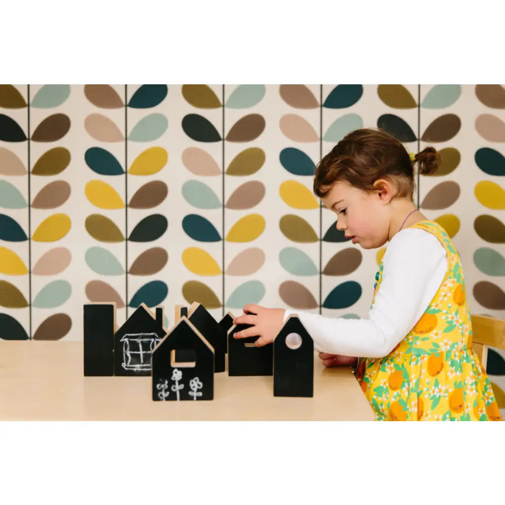 Child playing with small wooden house-shaped blocks.