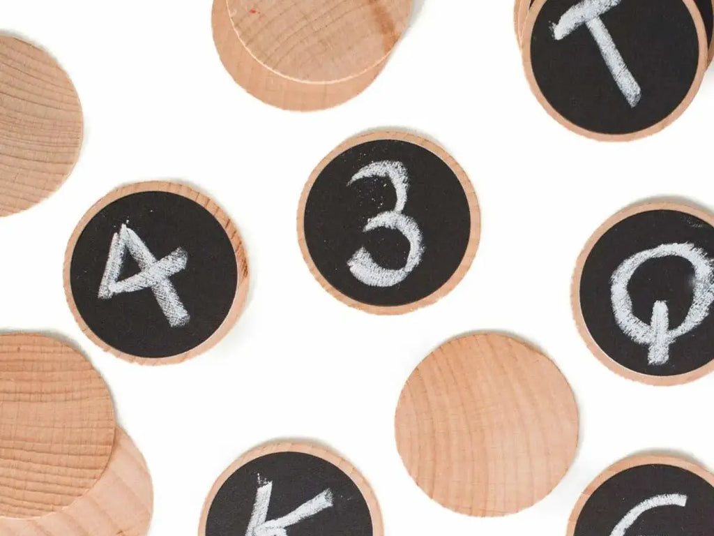Wooden discs with chalkboard surfaces displaying numbers and letters.