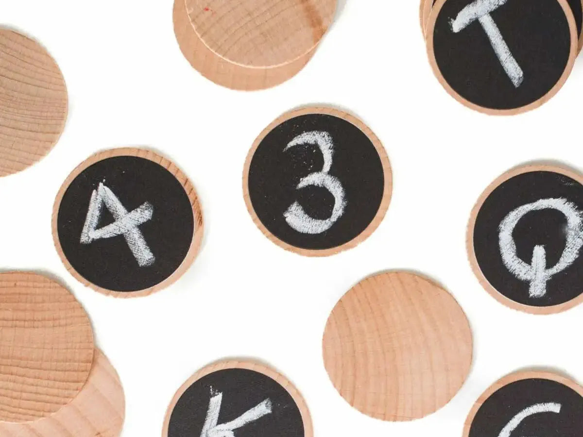 Wooden discs with chalkboard surfaces displaying numbers and letters.