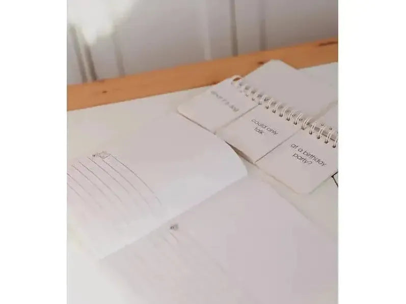Notebook or journal open on a wooden surface with loose papers nearby.