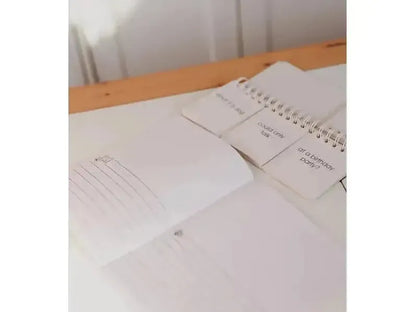 Notebook or journal open on a wooden surface with loose papers nearby.