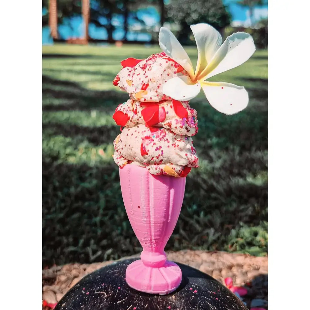 Ice cream sundae in a pink glass with a flower garnish.