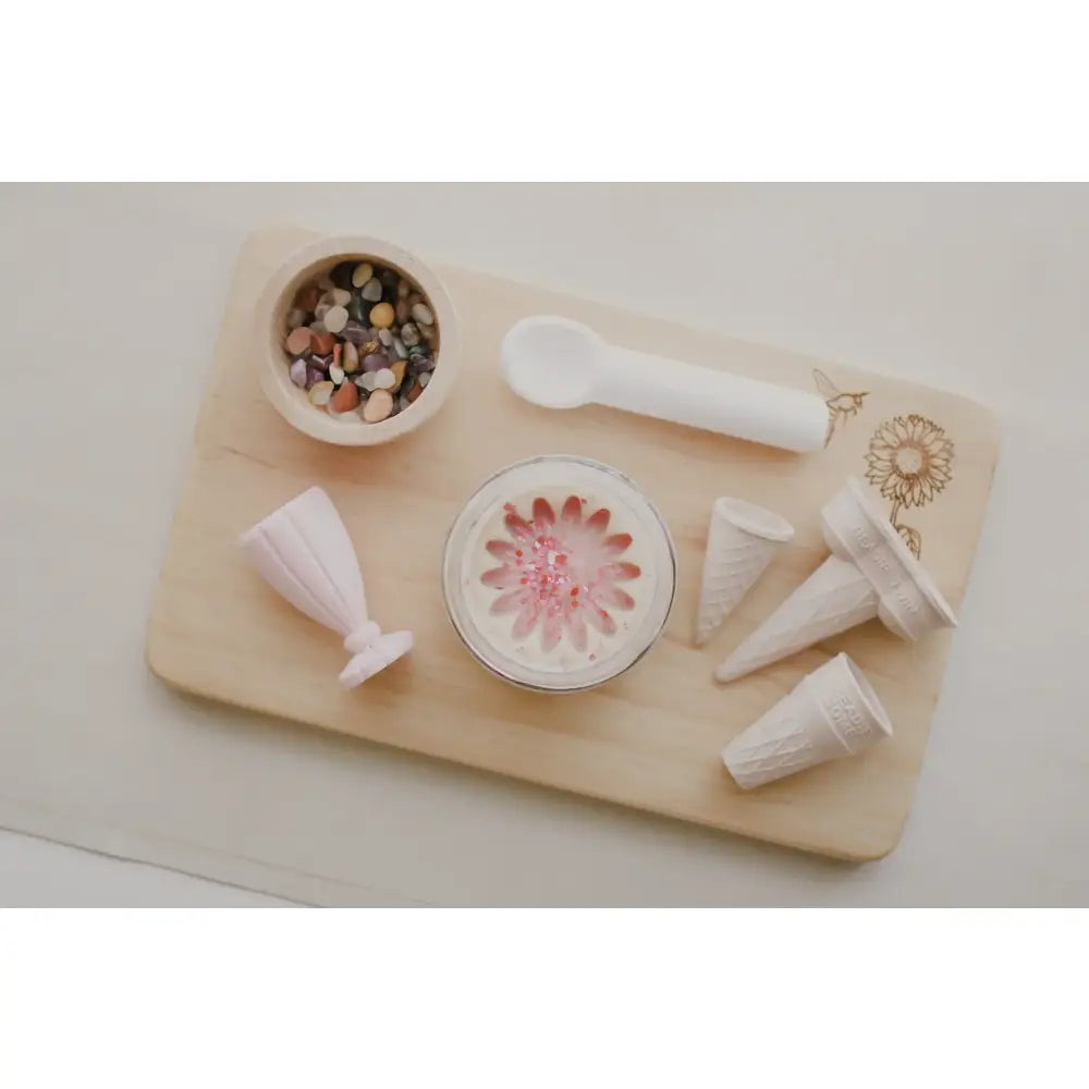 Wooden cutting board or serving tray with various white ceramic items and a pink floral dish.