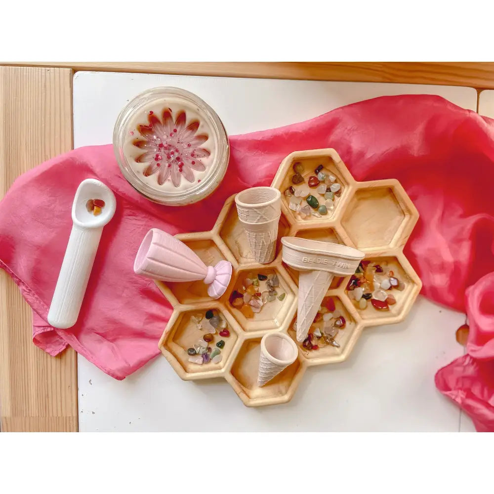 Hexagonal wooden tray with compartments containing colorful beads or small objects.