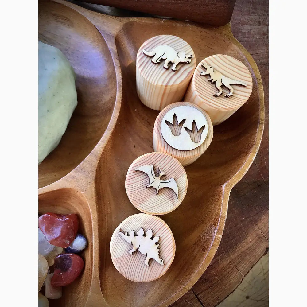 Wooden stamps or blocks with dinosaur and animal designs carved into their circular faces.