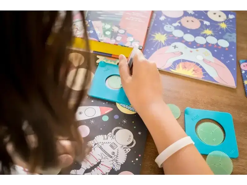 Child’s hand drawing or coloring on a space-themed illustration.