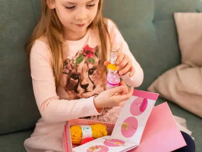 Young girl playing with a pink toy box or gift set containing small figurines.