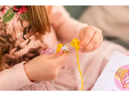 Kitten being adorned with a yellow ribbon or string.