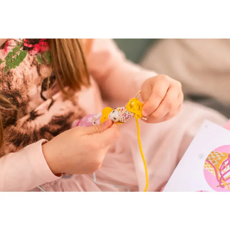 Kitten being adorned with a yellow ribbon or string.