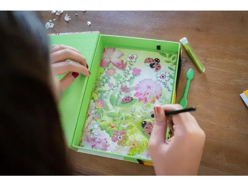 Green plastic tray containing a colorful drawing or artwork with floral and butterfly designs.