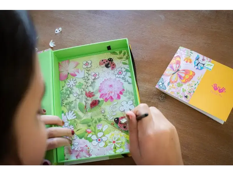 Colorful children’s book or notebook with floral designs being opened by small hands.