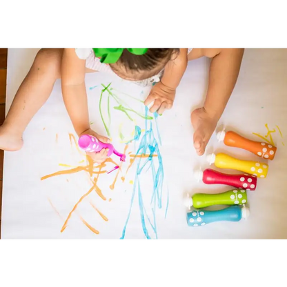 Child drawing with colorful chalk markers on a white surface.