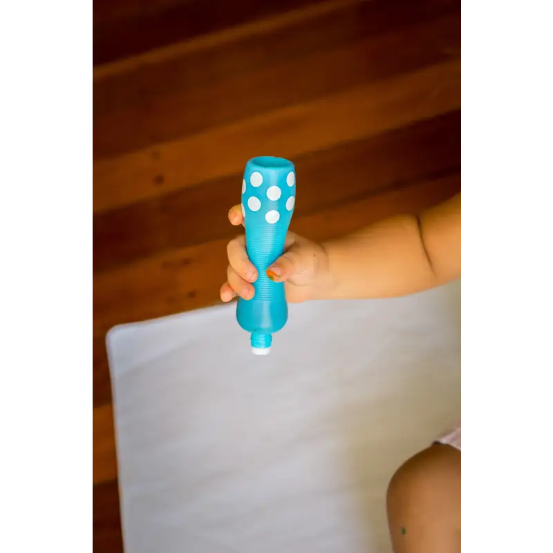 Blue plastic toy rattle with white polka dots held by a hand.