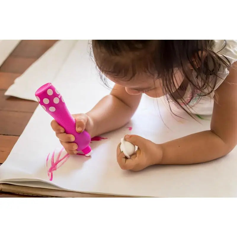 Child using a bright pink marker to draw on paper.