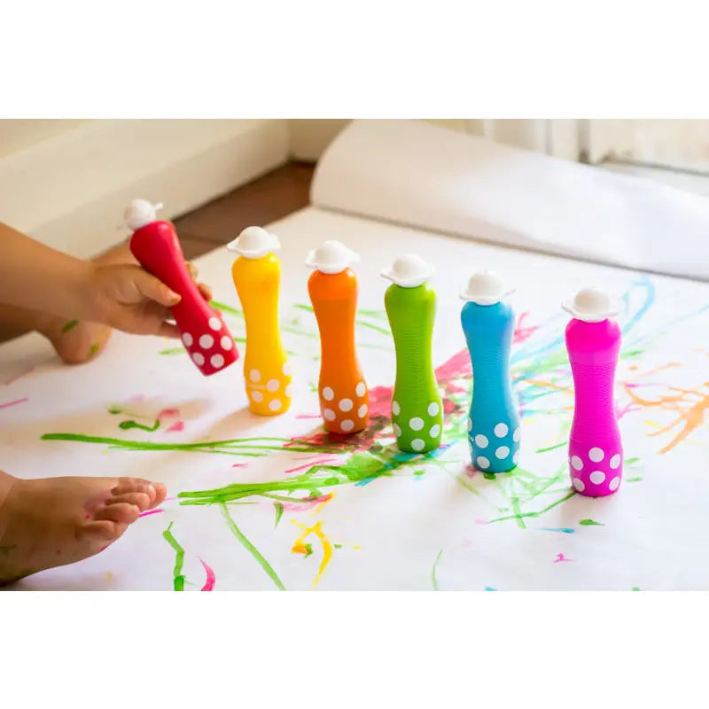 Colorful plastic bottles filled with paint arranged in a rainbow spectrum.