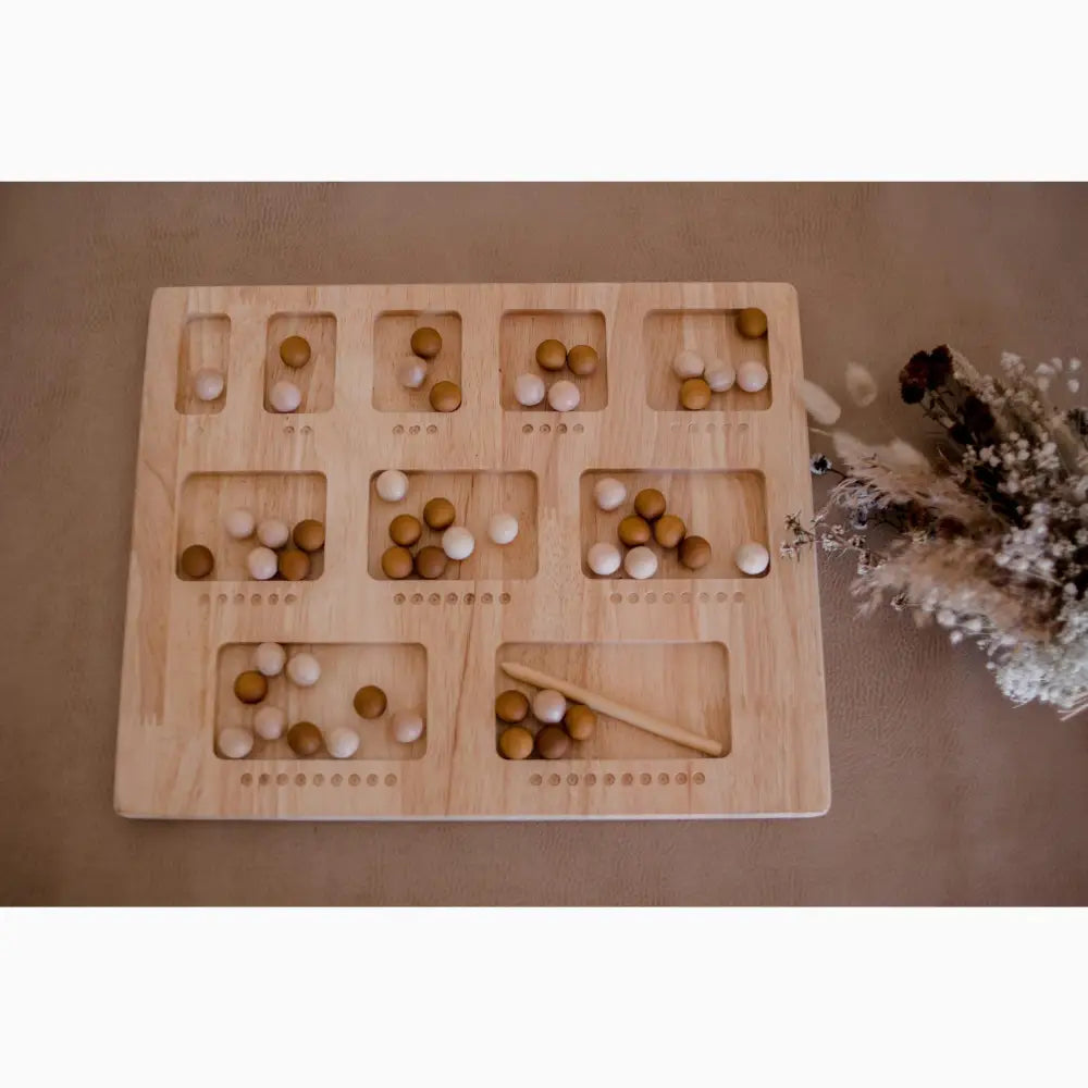 Wooden counting board with numbered compartments containing white and brown balls.