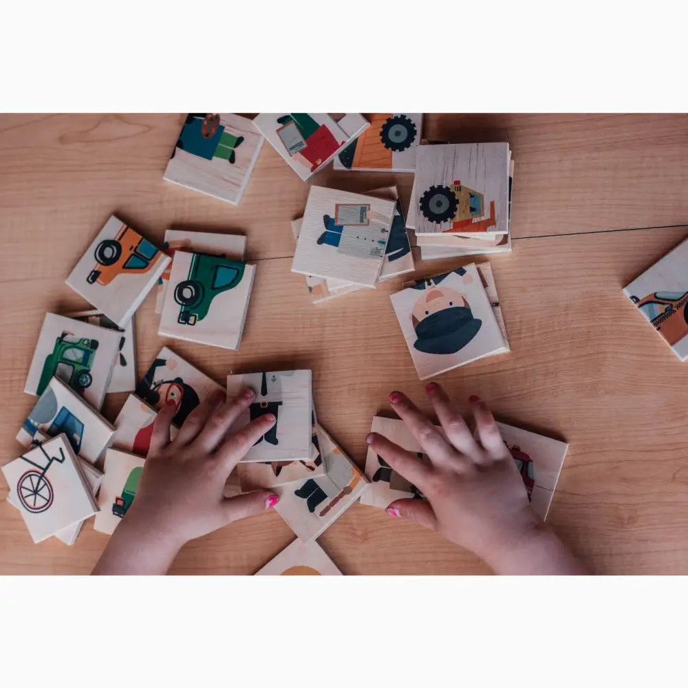 Memory card game with illustrated vehicle and transportation-themed tiles spread out on a wooden surface.