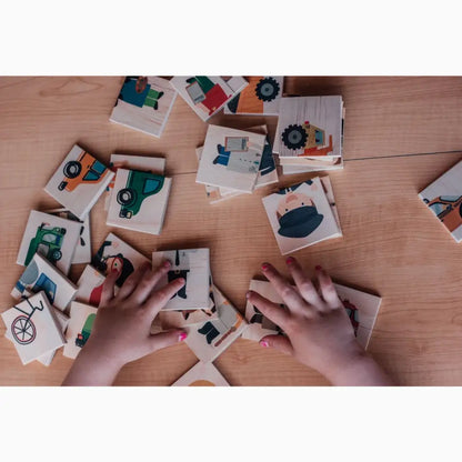Memory card game with illustrated vehicle and transportation-themed tiles spread out on a wooden surface.