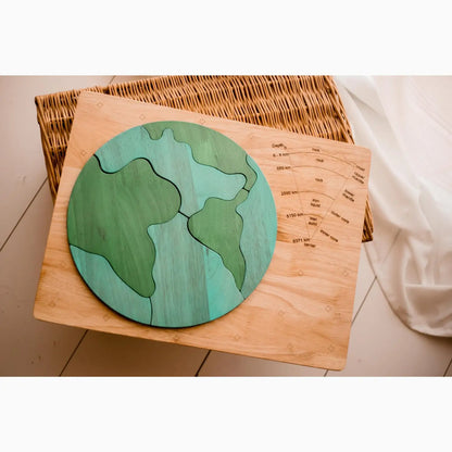 Wooden puzzle map of Earth with green and blue continents and oceans.