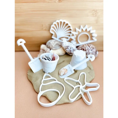 Clay or dough with various beach-themed cookie cutters and decorative elements.