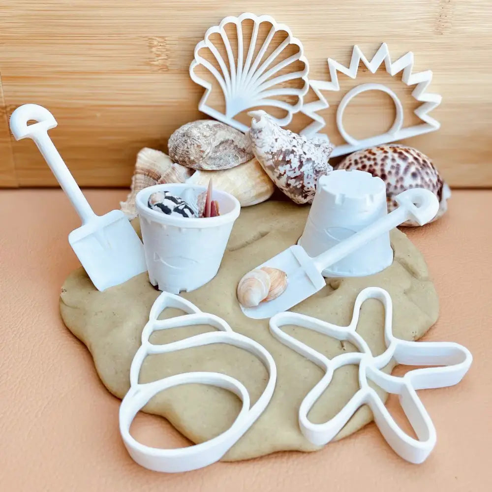 Beach-themed play dough set with shells and plastic molds for sand castle shapes.