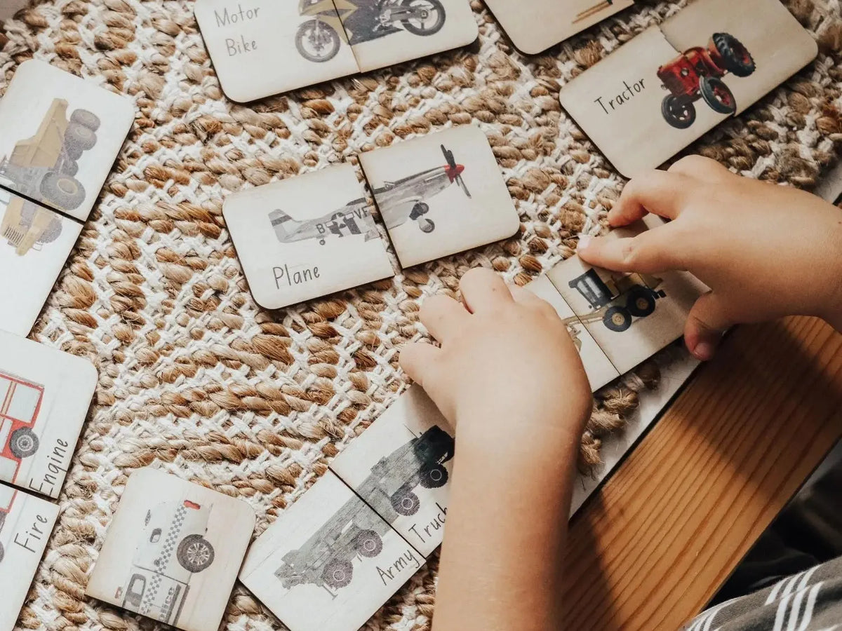 Wooden puzzle cards featuring various vehicle illustrations spread out on a textured rug.