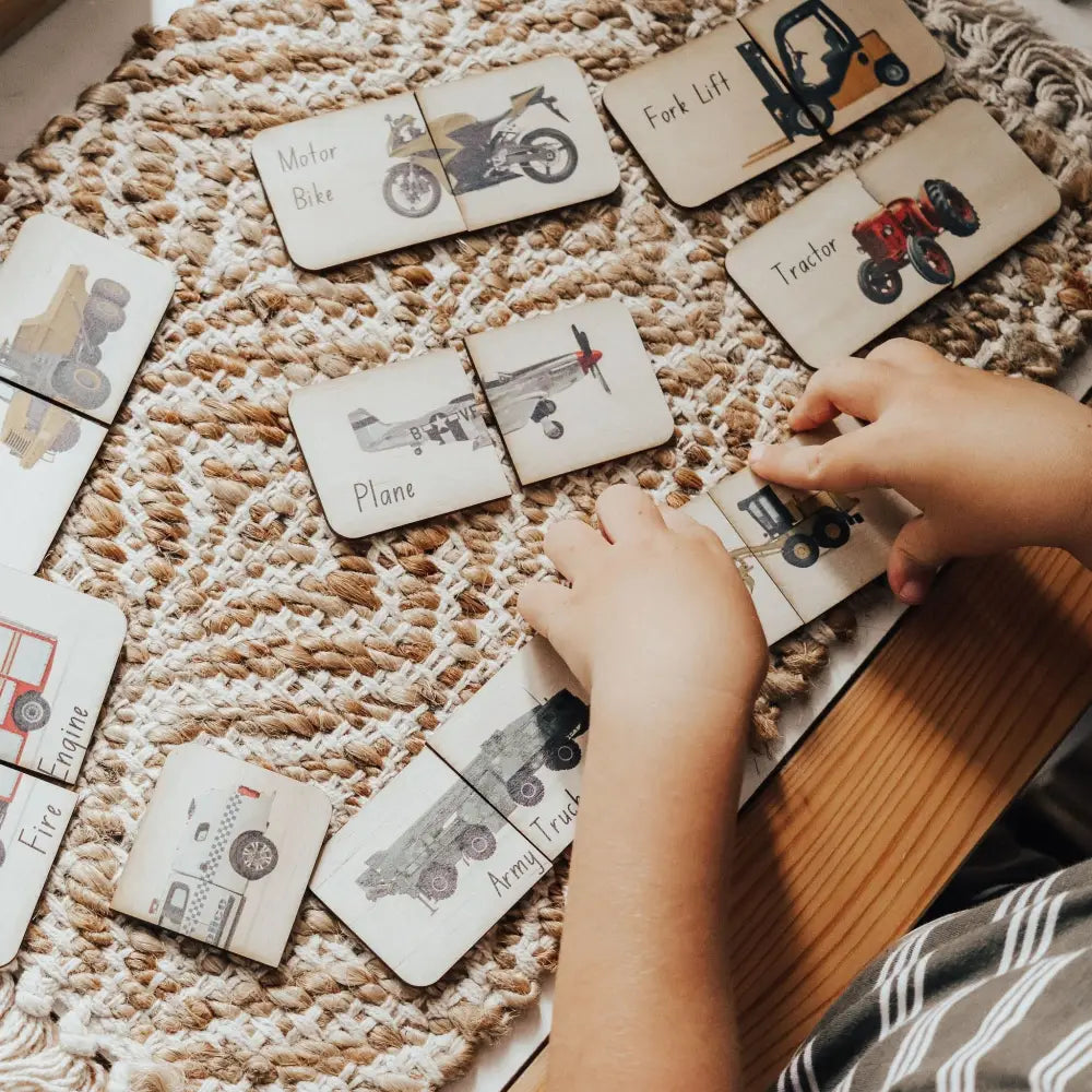 Wooden puzzle cards featuring various vehicle illustrations spread out on a textured rug.