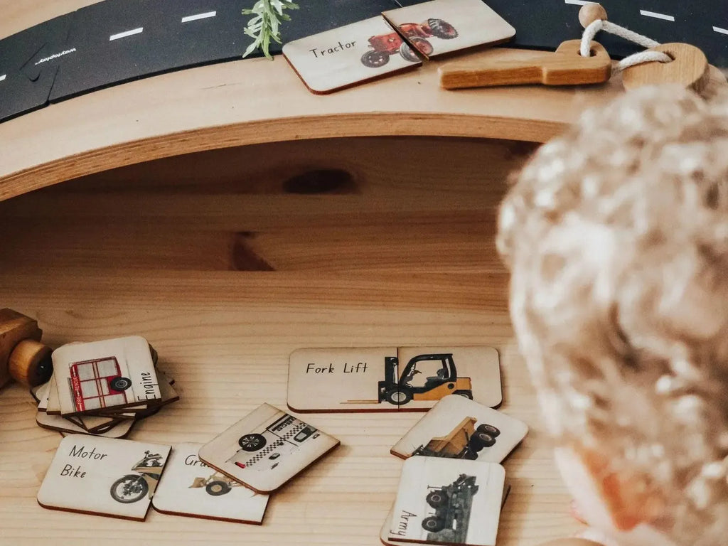 Wooden toy road or track with various vehicle-themed cards and accessories.