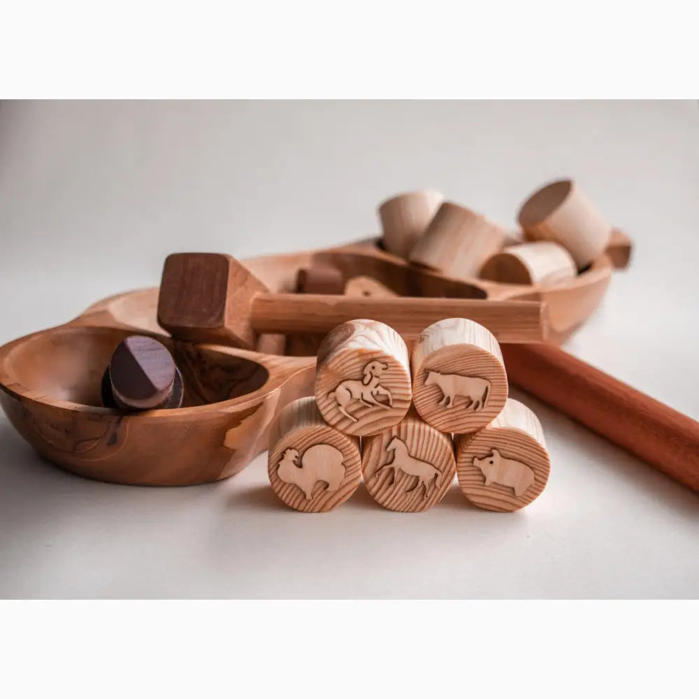 Wooden stamps with carved animal designs alongside wooden bowls and a mallet.