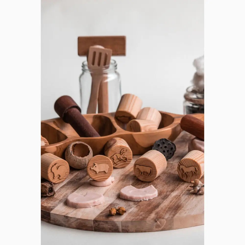 Wooden stamps or cookie molds with various animal designs carved into their circular faces.
