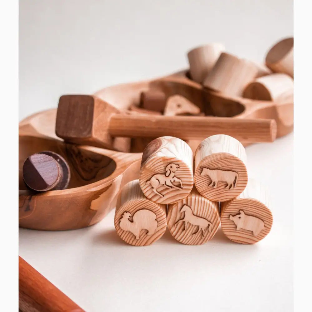 Wooden toy blocks with animal and nature designs carved on their circular faces.