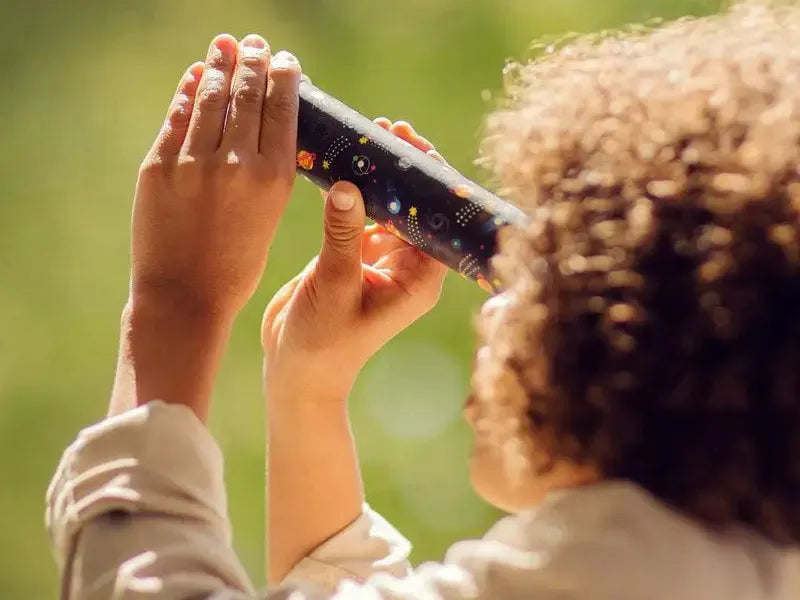 Kaleidoscope held up to the light by a child’s hands.
