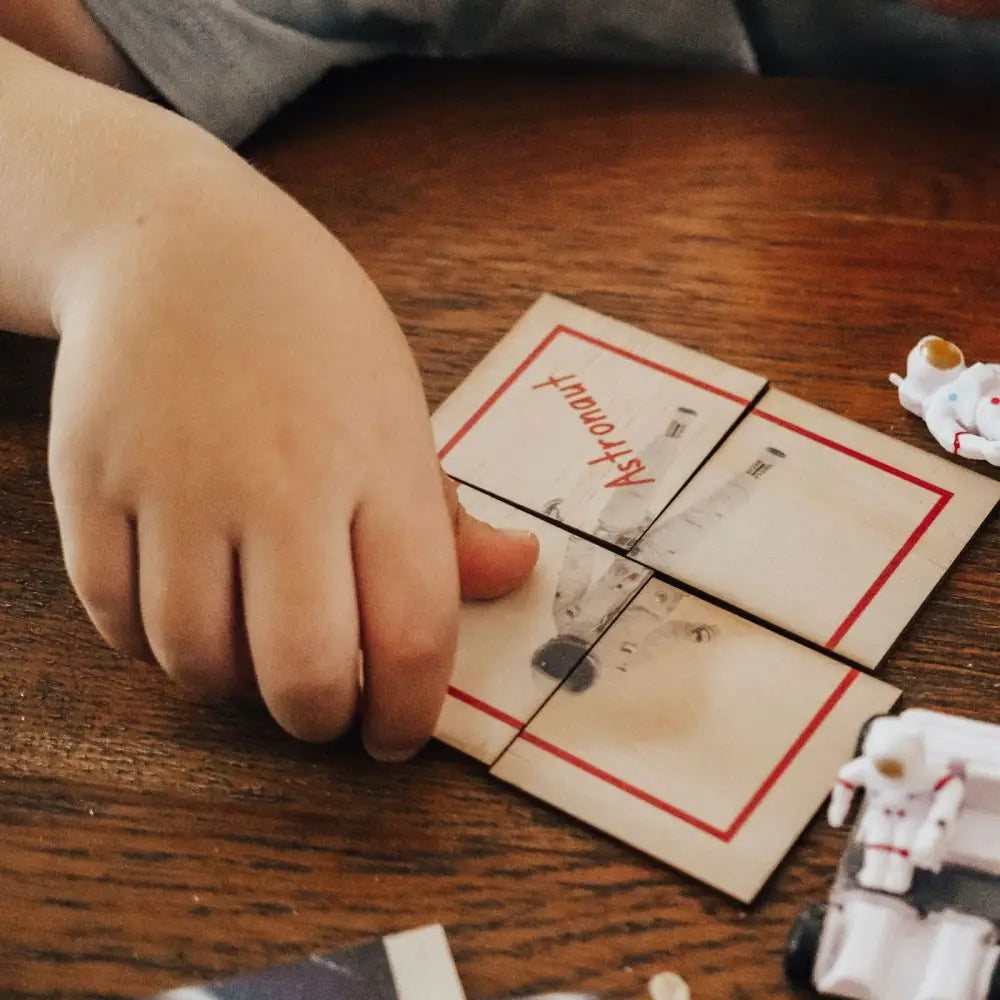 Mousetrap set on a wooden surface with a hand nearby.