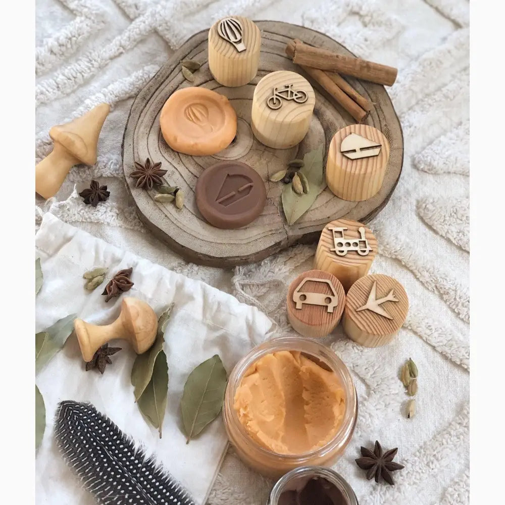 Wooden circular tray holding various wooden stamps, spices, and a jar of spread.