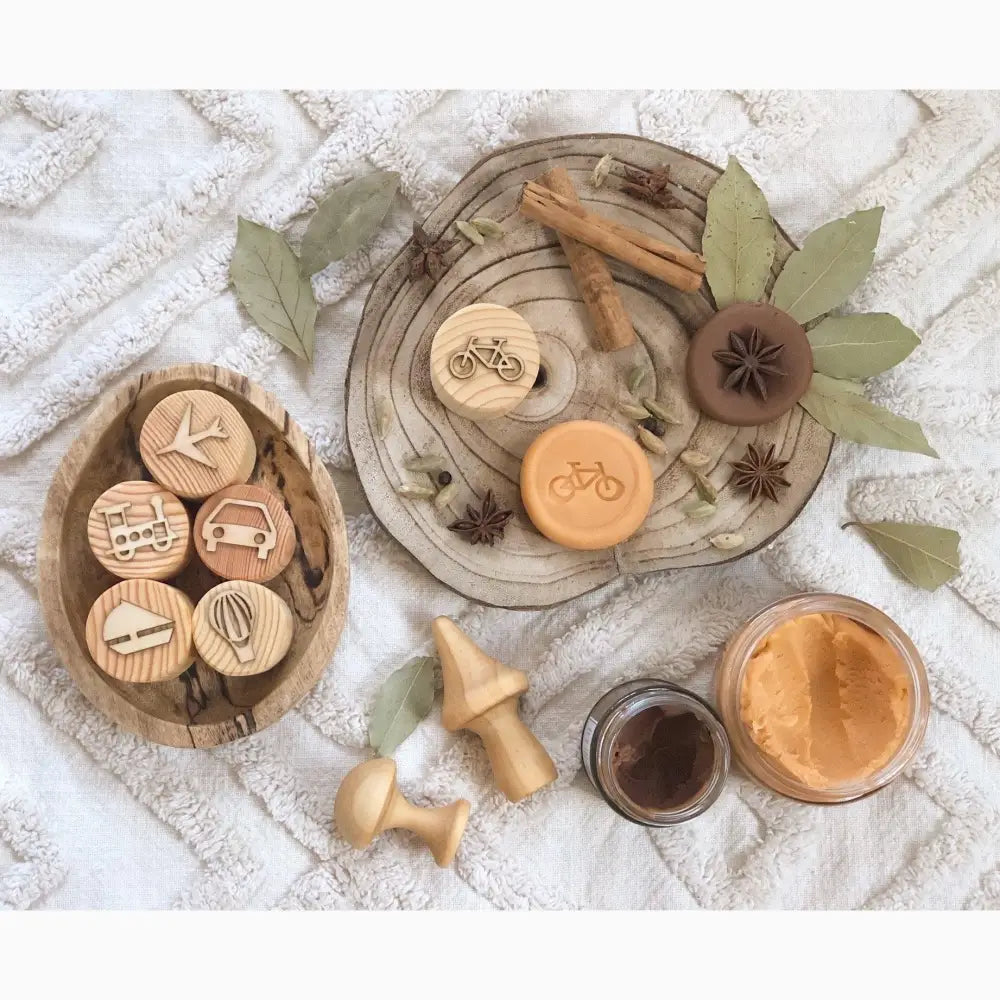 Wooden plates and bowls containing various natural objects and small wooden discs with engraved designs.