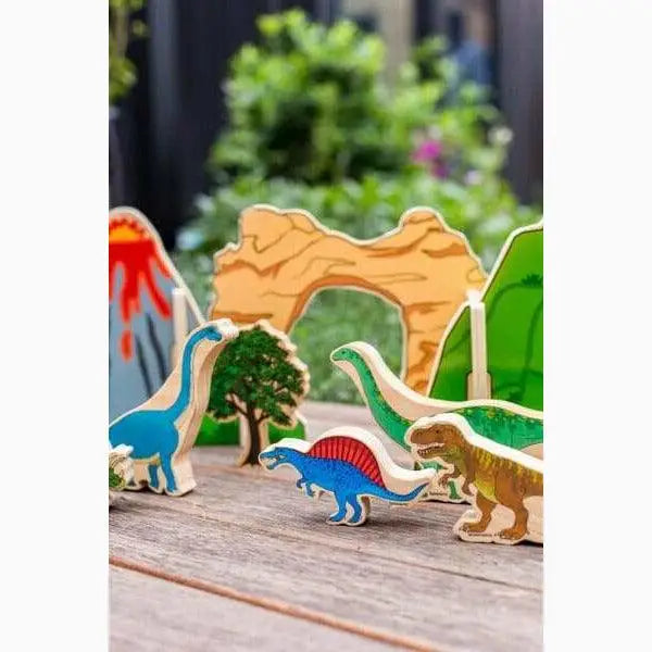 Colorful wooden dinosaur figurines and a tree on a wooden surface.