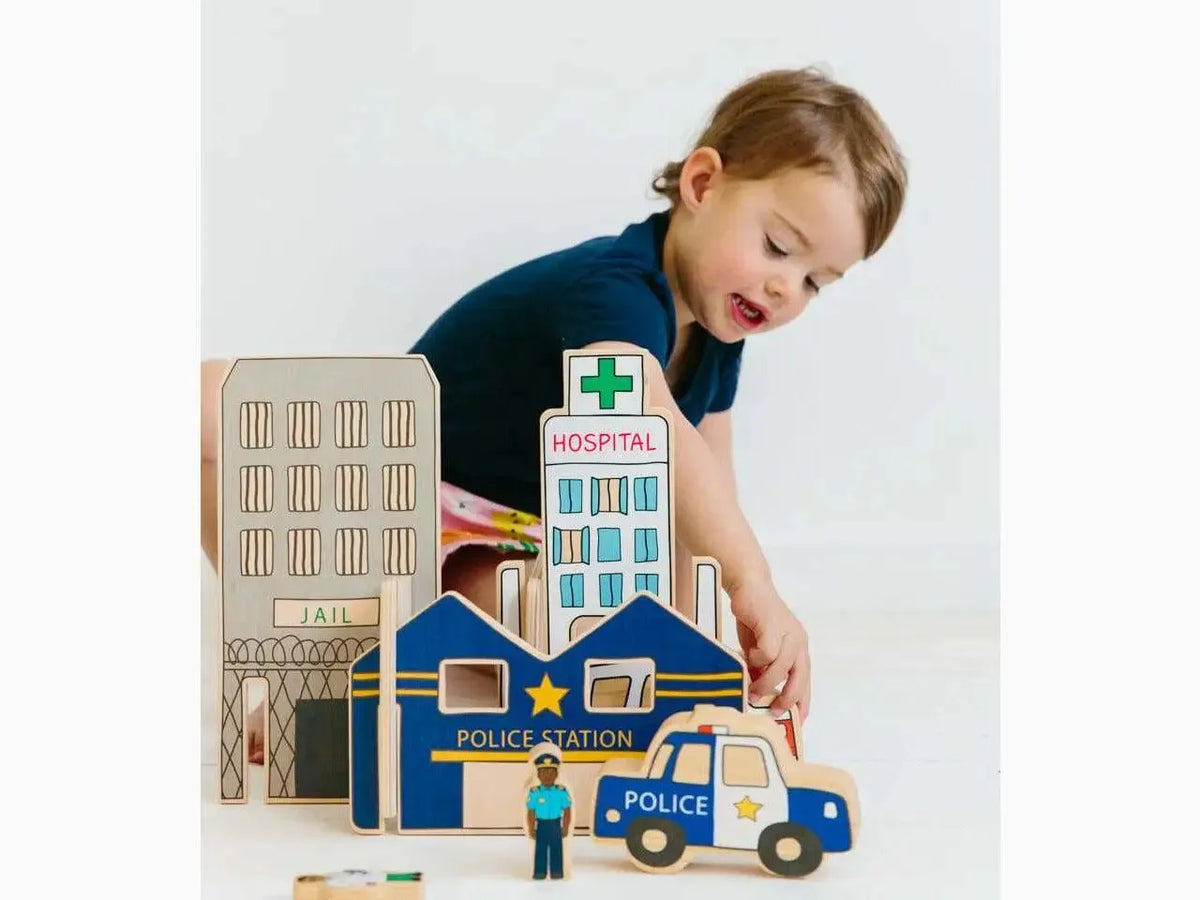 Wooden toy city playset featuring buildings and vehicles, including a police station and hospital.
