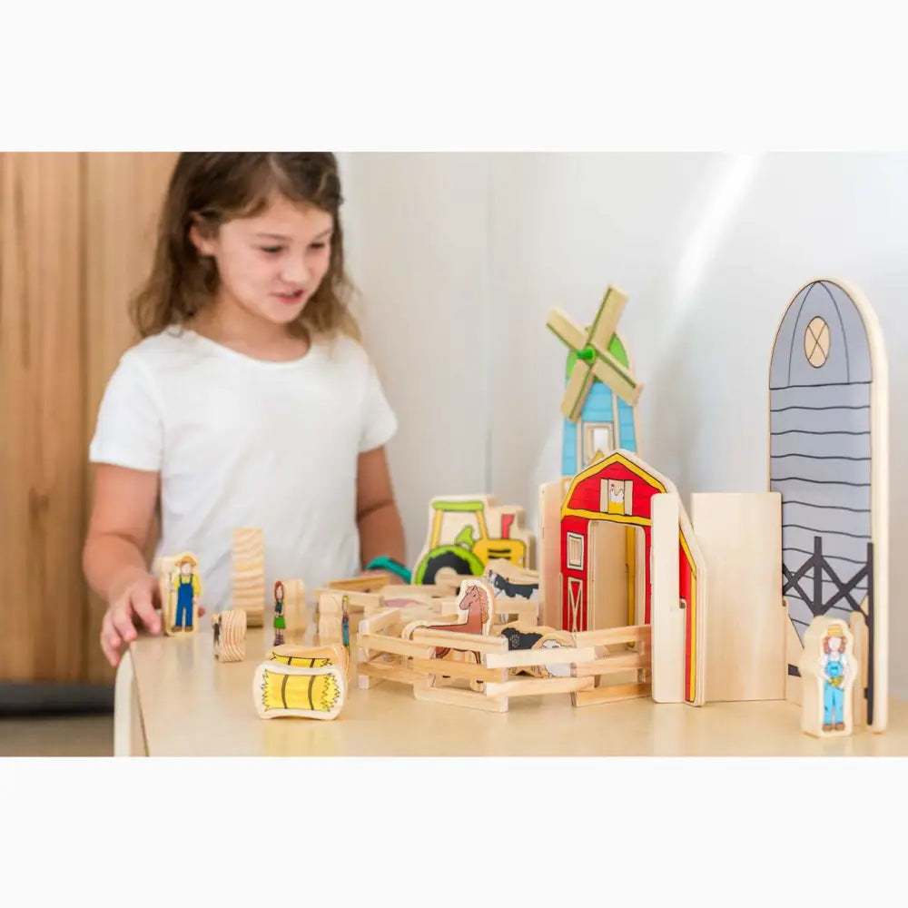 Wooden farm playset with colorful buildings, animals, and figures.