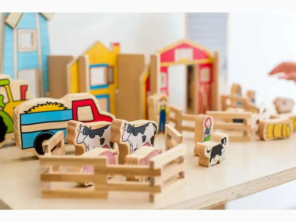 Wooden toy farm set with miniature animals, buildings, and vehicles.